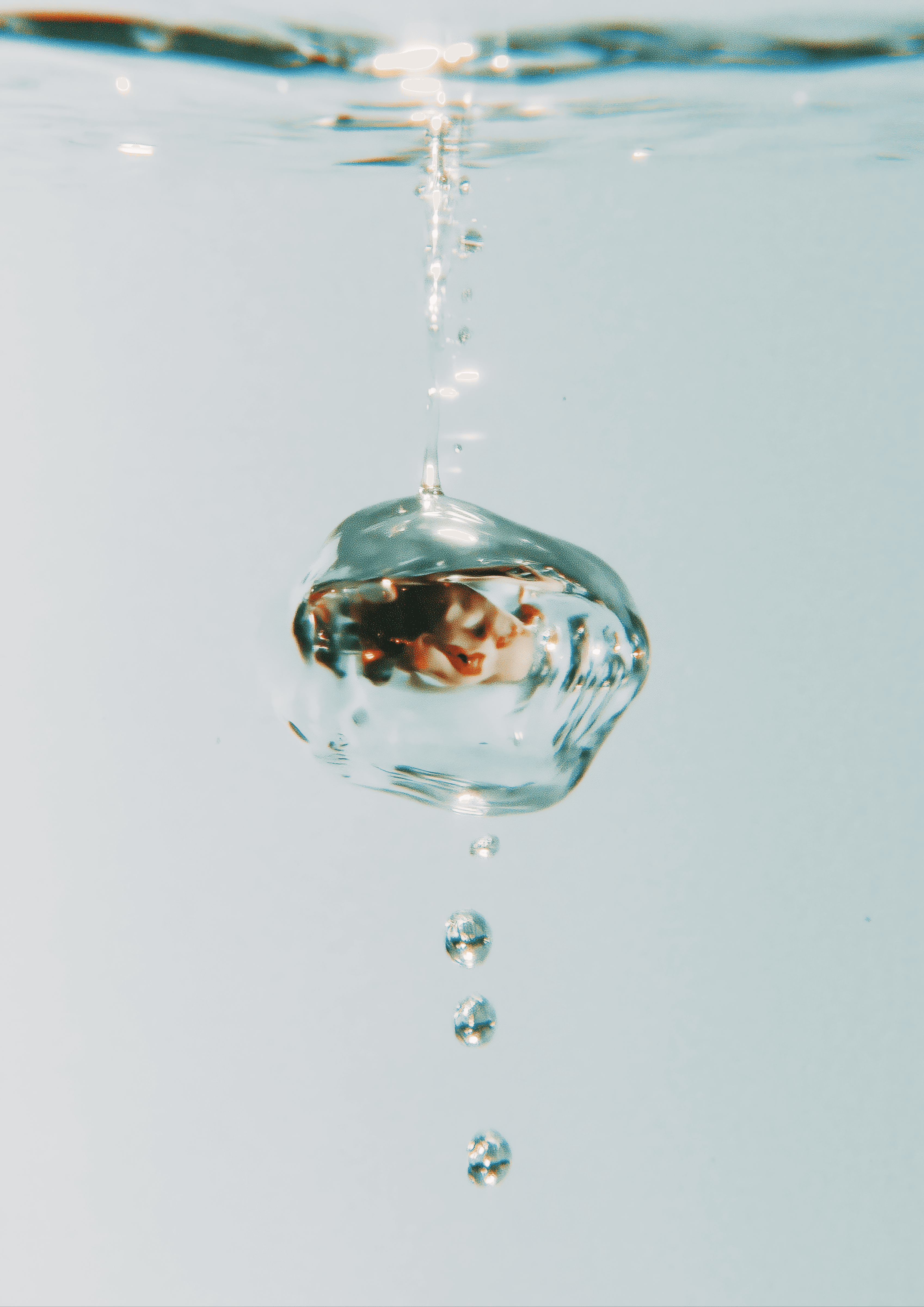 Underwater air bubble rising with a trail of droplets in clear aqua water—minimal, clean visual texture.